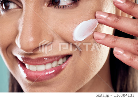Woman, cream and thinking to apply in studio, hydration and cleaning or skincare on blue background. Female person, beauty and plan for facial treatment or cosmetics, pamper routine and sunscreen 116304133