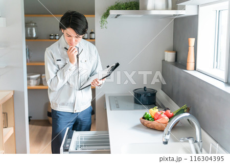キッチンの食洗機・食器洗い乾燥機を診断・チェック・査定する作業服姿の男性ビジネスマン 116304395