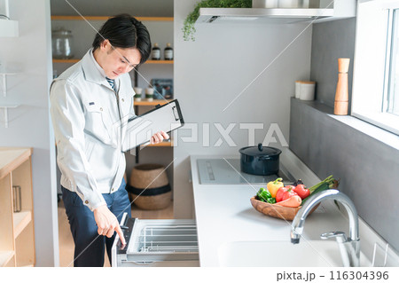 キッチンの食洗機・食器洗い乾燥機を診断・チェック・査定する作業服姿の男性ビジネスマン 116304396