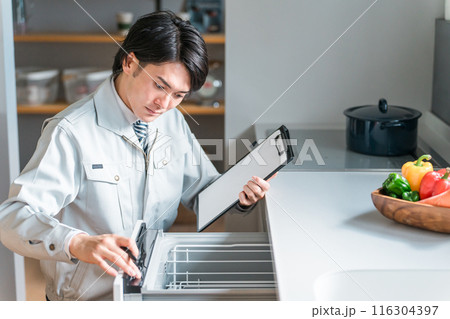 キッチンの食洗機・食器洗い乾燥機を診断・チェック・査定する作業服姿の男性ビジネスマン 116304397