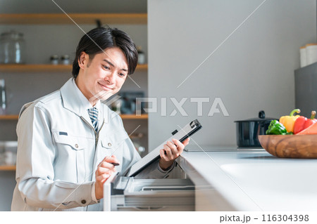 キッチンの食洗機・食器洗い乾燥機を診断・チェック・査定する作業服姿の男性ビジネスマン 116304398