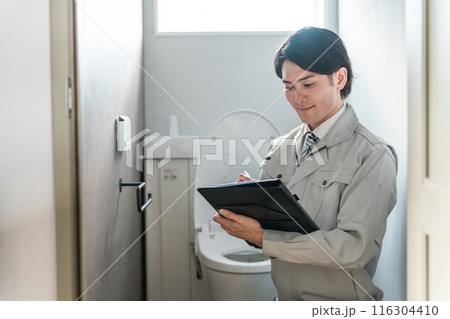 トイレをチェックする作業着姿の設備屋・水道屋の男性ビジネスマン 116304410