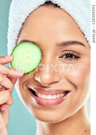 Woman, cucumber and skincare or beauty in studio, eco friendly and nutrition to hydrate skin. Female person, glow and organic benefits or facial treatment in portrait, cosmetics and blue background Woman, cucumber and skincare or beauty in studio, eco friendly and nutrition to hydrate skin. Female person, glow and organic benefits or facial treatment in portrait, cosmetics and blue background 116304501