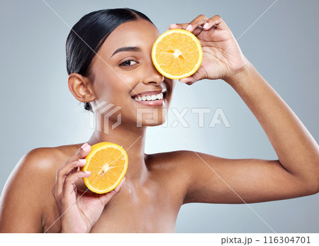 Indian woman, orange and smile for organic beauty, hand and fruit on white background. Citrus, face or vitamin c for hydrated skin or body care, studio and vegan skincare with happy female person 116304701