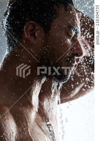 Man, shower and washing in studio for facial, cosmetics and cleaning on gray background. Male person, profile and water drops for skincare treatment or dermatology, grooming and hydration beauty Man, shower and washing in studio for facial, cosmetics and cleaning on gray background. Male person, profile and water drops for skincare treatment or dermatology, grooming and hydration beauty 116304735
