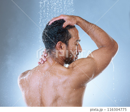 Shower, hair care and man in studio with water splash for hygiene, grooming or shampoo on blue background. Back, body and Asian model washing for natural treatment, wellness or morning routine 116304775