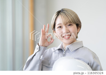 作業服を着てヘルメットを持つ金髪ショートヘアの若い女性(OK、髪色自由、自分らしく働く、職場環境) 作業服を着てヘルメットを持つ金髪ショートヘアの若い女性(OK、髪色自由、自分らしく働く、職場環境) 116305324