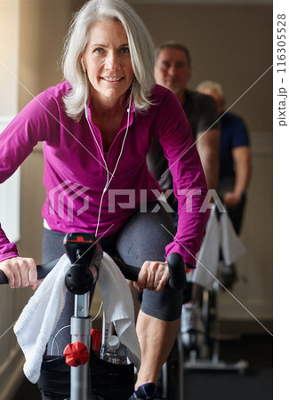 Senior, portrait or happy woman on exercise bike in training or workout for cycling, health or wellness. Music, earphones or elderly sports person on gym bicycle for fitness, spinning class or energy 116305528
