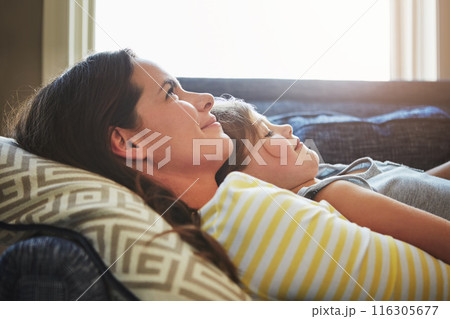 Love, rest and mother cuddle her child while relaxing on sofa in the living room of their home. Happiness, bonding and young mom embracing and hugging daughter with care in their family house Love, rest and mother cuddle her child while relaxing on sofa in the living room of their home. Happiness, bonding and young mom embracing and hugging daughter with care in their family house 116305677