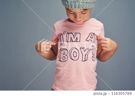 Hands, child and point at print on shirt for gender identity, style and edgy fashion model by blue background. Boy, toddler and kid with pink clothes for choice, learning and show text with promotion Hands, child and point at print on shirt for gender identity, style and edgy fashion model by blue background. Boy, toddler and kid with pink clothes for choice, learning and show text with promotion 116305789