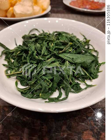 Boiled cassava leaf vegetables are served as a side dish for rice 116305886