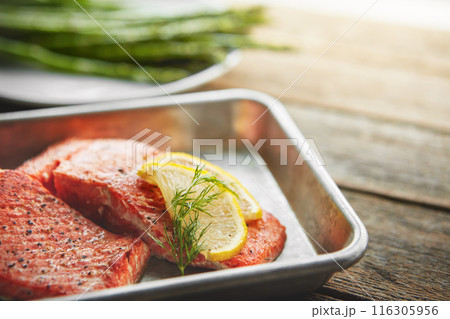 Gourmet, lemon and grilled salmon with asparagus for healthy, wellness and nutrition fine dining cuisine. Food, meal and diet dish of fish, vegetables and citrus fruit for dinner on wooden table. 116305956