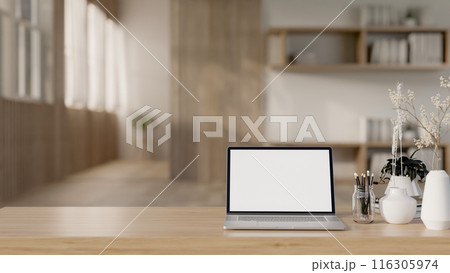 A laptop computer mockup and accessories on a wooden tabletop in a Scandinavian minimalist room. A laptop computer mockup and accessories on a wooden tabletop in a Scandinavian minimalist room. 116305974