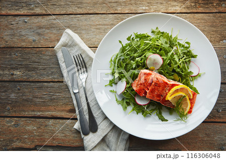 Food, fish protein and salad on table with nutrition, lunch and lose weight with pescatarian diet. Salmon, rocket leaves and dinner plate above with cholesterol for gut health and digestion benefits Food, fish protein and salad on table with nutrition, lunch and lose weight with pescatarian diet. Salmon, rocket leaves and dinner plate above with cholesterol for gut health and digestion benefits 116306048