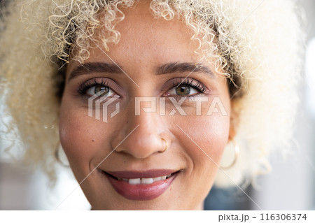 In modern office, biracial young female with curly blonde hair, smiling In modern office, biracial young female with curly blonde hair, smiling 116306374
