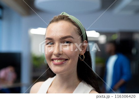 In modern office, a Caucasian female with a green headband, smiling In modern office, a Caucasian female with a green headband, smiling 116306420