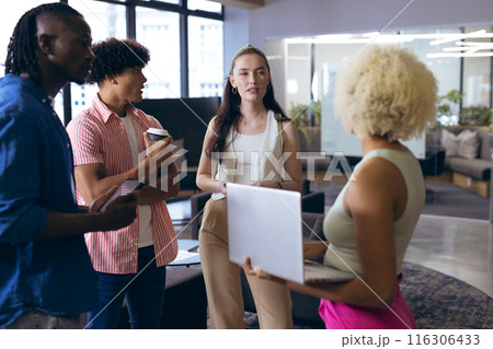 In modern office, diverse young team discussing with laptops and coffee 116306433