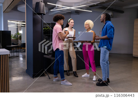 In modern office, diverse young team holding devices, discussing work In modern office, diverse young team holding devices, discussing work 116306443