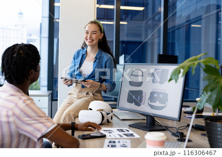Diverse young team in casual clothes discusses over a tablet in a modern office Diverse young team in casual clothes discusses over a tablet in a modern office 116306467
