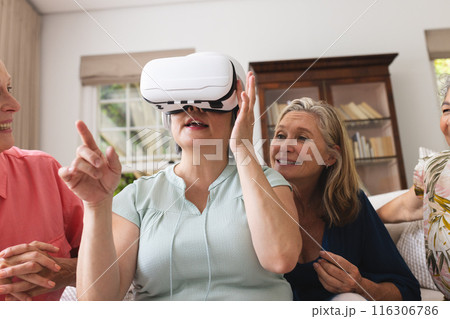 Diverse senior female friends enjoying VR at home Diverse senior female friends enjoying VR at home 116306786