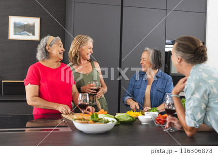 Diverse senior female friends enjoying meal together at home 116306878