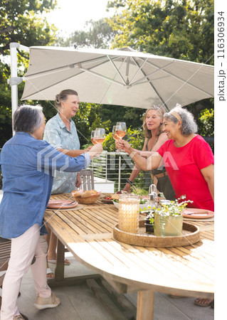 Diverse senior female friends enjoying toast outdoors Diverse senior female friends enjoying toast outdoors 116306934
