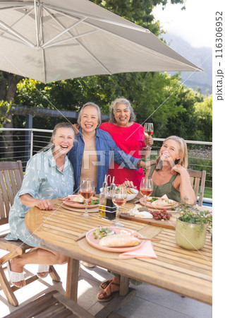 Diverse senior female friends enjoying meal outdoors 116306952