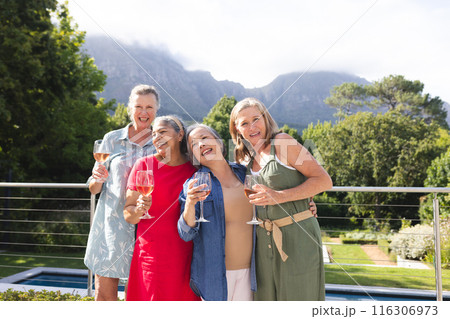 Diverse senior female friends enjoying wine outdoors Diverse senior female friends enjoying wine outdoors 116306973