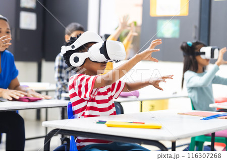 In school, diverse students wearing virtual reality headsets are reaching out in the classroom 116307268