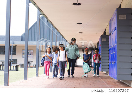In school, diverse group of students walking with their teacher outdoors In school, diverse group of students walking with their teacher outdoors 116307297