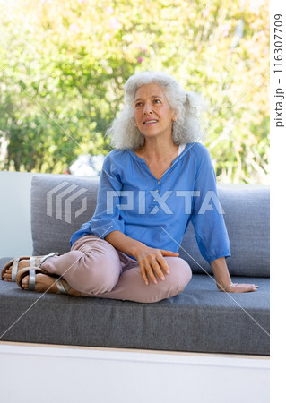 Outdoors, Caucasian senior woman wearing blue shirt, sitting on gray sofa 116307709