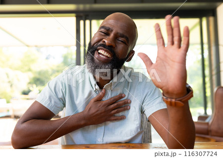 At home, African American senior man laughing, waving during video call 116307724