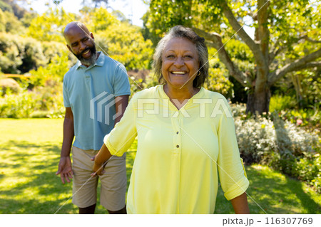 A diverse senior couple enjoying outdoors in sunny garden 116307769