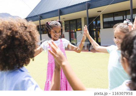 In school, two biracial girls and one biracial boy are playing outside 116307958