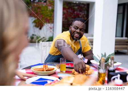 Happy diverse group of friends talking and having dinner at balcony with flags of usa 116308447