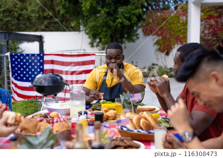 Happy diverse group of friends talking and having dinner at balcony with flags of usa Happy diverse group of friends talking and having dinner at balcony with flags of usa 116308473