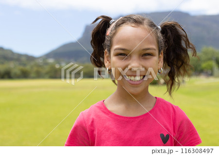 Biracial girl with a bright smile, wearing a pink shirt with a heart design, with copy space 116308497