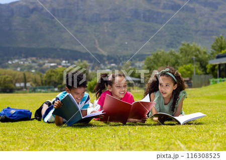Biracial boy and girls are reading books on a sunny grass field Biracial boy and girls are reading books on a sunny grass field 116308525