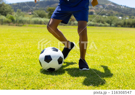 Biracial boy plays soccer on a sunny field, showcasing his skills with a black and white ball Biracial boy plays soccer on a sunny field, showcasing his skills with a black and white ball 116308547