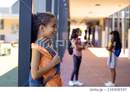 Biracial girl with a polka dot dress stands by a pillar at school, smiling, with copy space Biracial girl with a polka dot dress stands by a pillar at school, smiling, with copy space 116308597