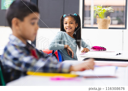 In school, young biracial boy and girl focusing on their studies in classroom In school, young biracial boy and girl focusing on their studies in classroom 116308676