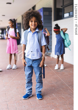 In school, young African American boy stands smiling with backpack outdoors 116308751