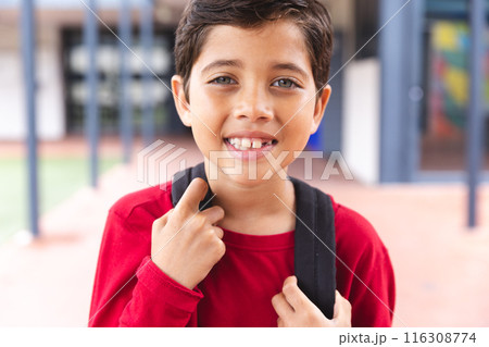 In school outdoors, biracial young boy wearing a backpack is smiling In school outdoors, biracial young boy wearing a backpack is smiling 116308774