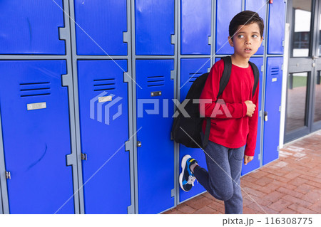 In school, young biracial male student leaning against blue lockers with copy space outdoors In school, young biracial male student leaning against blue lockers with copy space outdoors 116308775