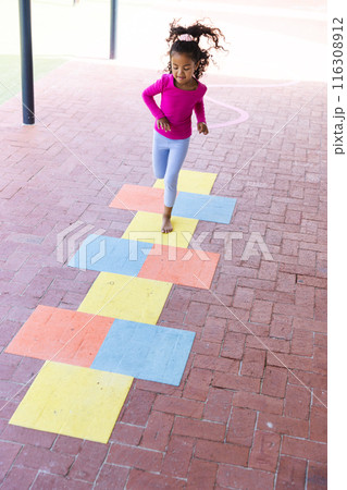 In school, young biracial girl is playing hopscotch outdoors with copy space In school, young biracial girl is playing hopscotch outdoors with copy space 116308912