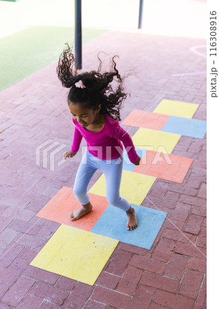 In school, young biracial girl is playing hopscotch alone outdoors In school, young biracial girl is playing hopscotch alone outdoors 116308916