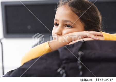In school, young biracial female student resting chin on hands, looking away in the classroom In school, young biracial female student resting chin on hands, looking away in the classroom 116308947