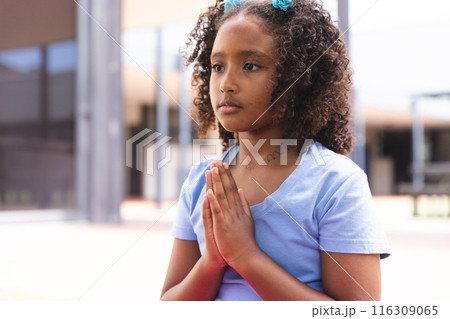 Biracial girl praying outdoors, with copy space 116309065