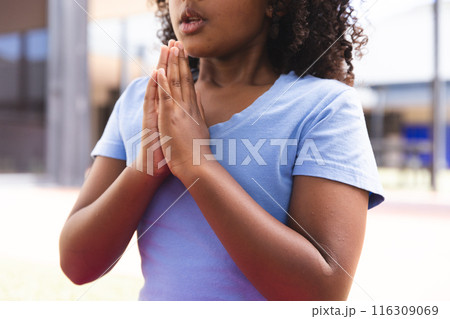 Biracial girl practices yoga outdoors at school Biracial girl practices yoga outdoors at school 116309069