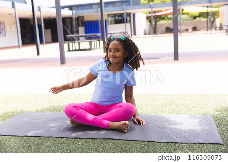 Biracial girl practices yoga at school, with copy space 116309073